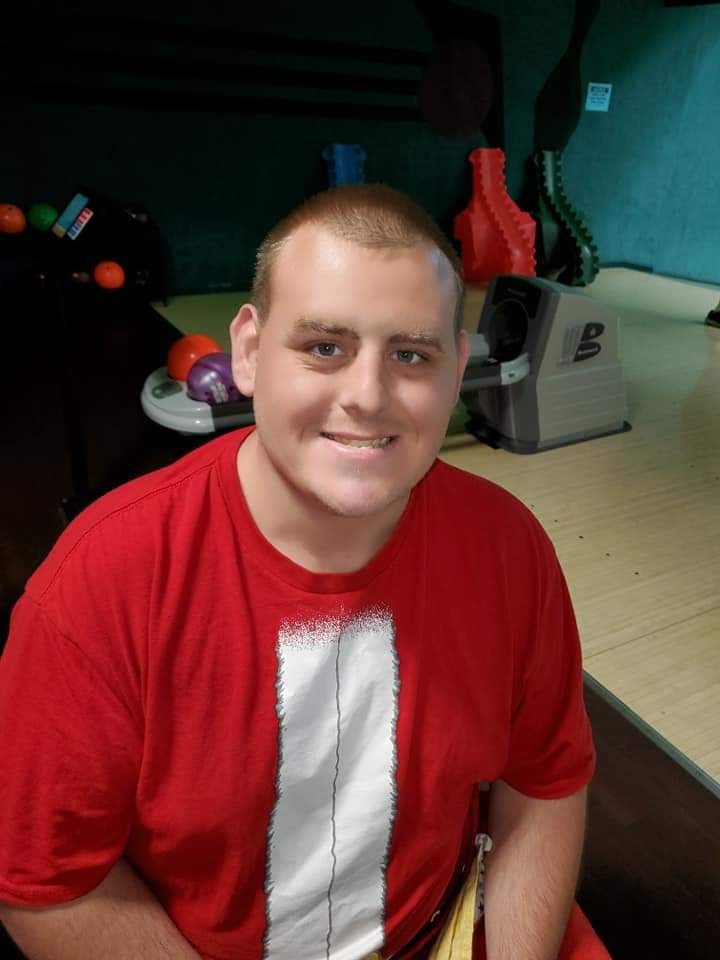 Image of a young man, smiling, wearing a red t-shirt.